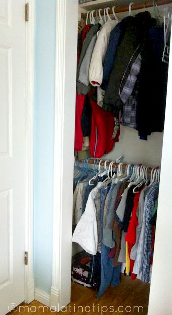 The interior of a closet with kids jacket on the top part and shirts in the bottom part. 