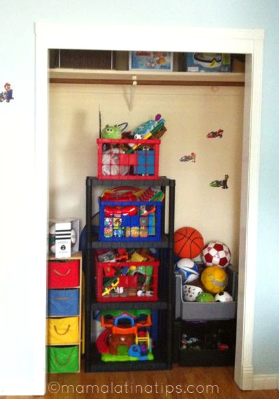The interior of a closet with three tall organizers with toys and balls. 