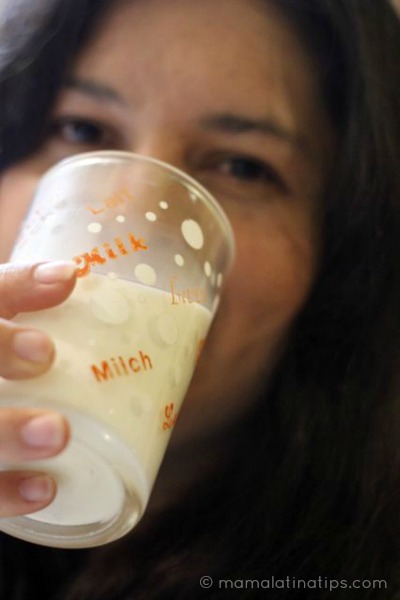Woman drinking milk from a glass that says milk and milch