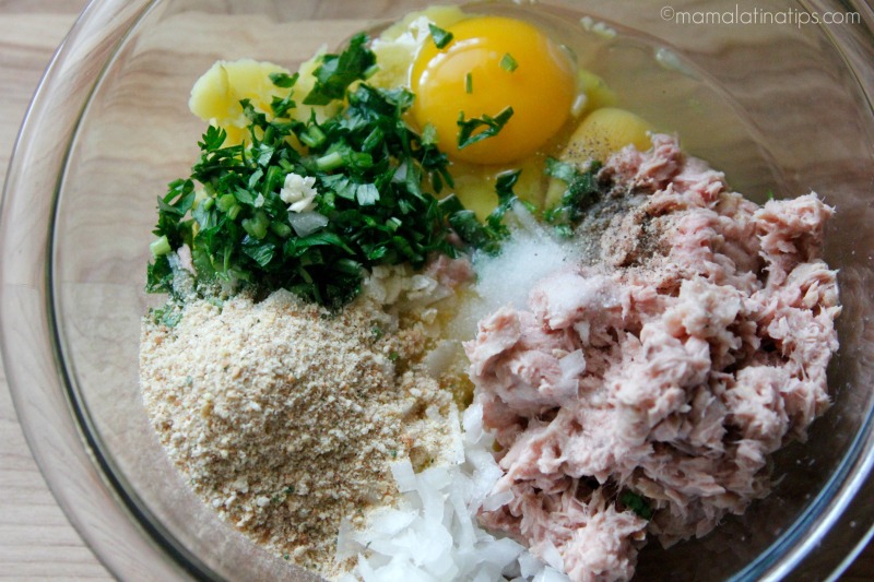 tuna, chopped onion, chopped parsley, bread crumbs and eggs in a glass bowl.