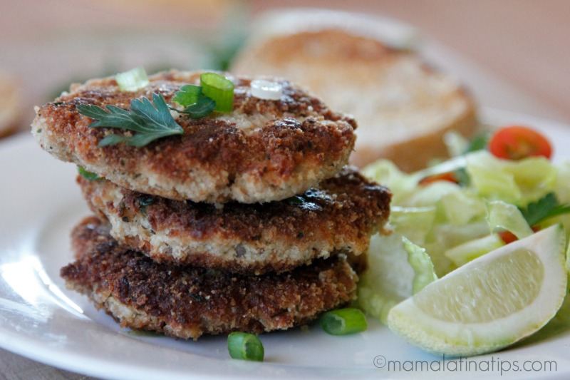 A tower of three crunchy una patties with a green salad and a slice of lime on the side. 