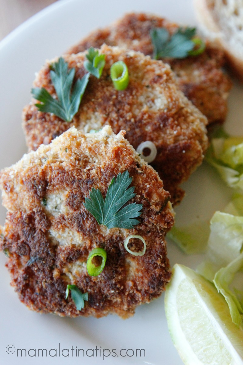 3 tortitas de atún en un plato blanco con ensalada y una rebanada de limón a un lado. 