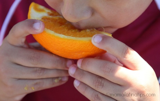 Kid eating an orange after a soccer game by mamalatinatips.com