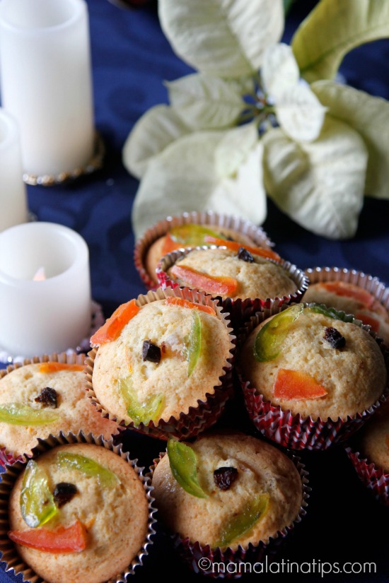 Muffins con fruta cristalizada sobre un mantel azul rey y junto a unas velas.