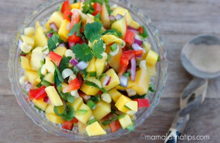 A bowl of mango salsa on a wooden table.