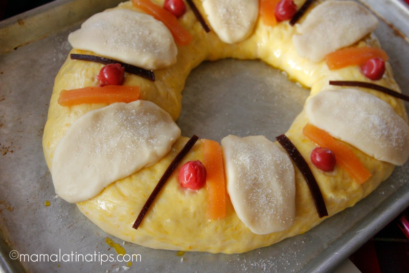 Vista en detalle de un roscón de reyes con cerezas, azúcar y membrillo, antes de hornear. 