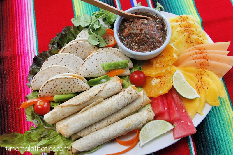 Platón con taquitos y quesadillas en tortillas de harina con salsa roja