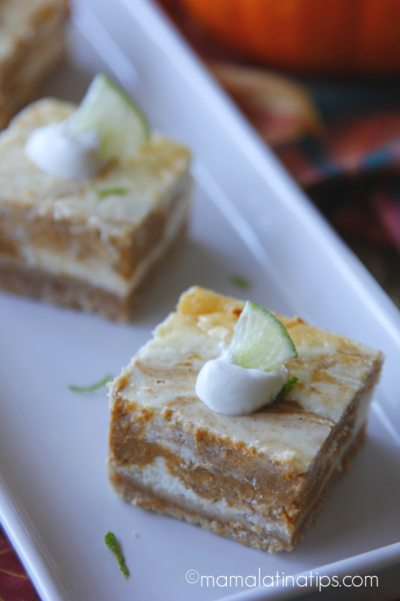 Close up of a square marbled cheesecake bar with a dollop of whipped cream and a small slice of lime on top.