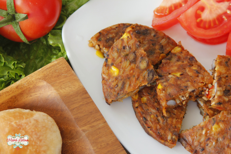 Bread roll, black bean patties and tomato on a white plate