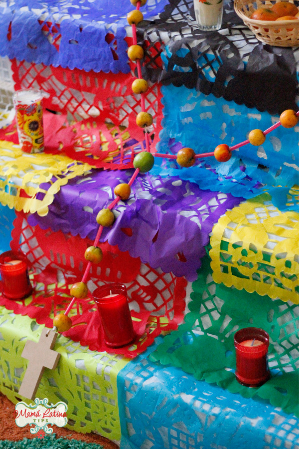 Layers of colorful papel picado covering several levels of a Day of the Dead altar.