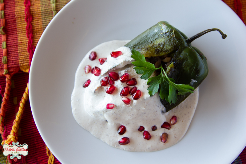 A stuffed poblano pepper covered with walnut sauce, parsley and pomegranate seeds