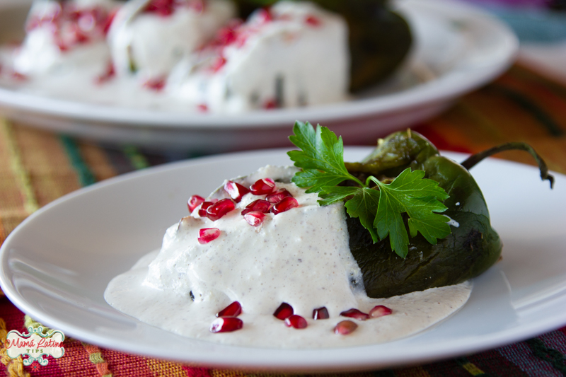 A stuffed poblano pepper in walnut sauce (chile en nogada) covered with pomegranate seeds and parsley