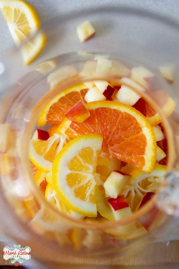 Clear pitcher with sliced oranges and lemons and apples