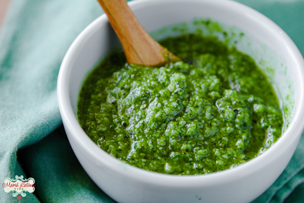 pesto de albahaca en tazón blanco con una cuchara de madera