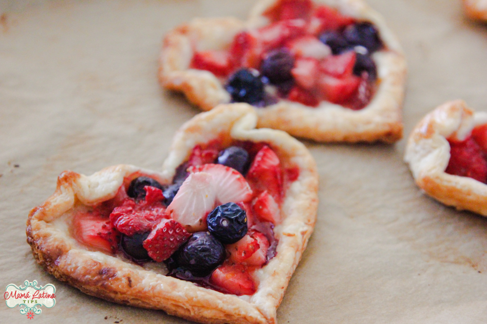 Two heart-shaped fruit tarts on top of beige parchment paper