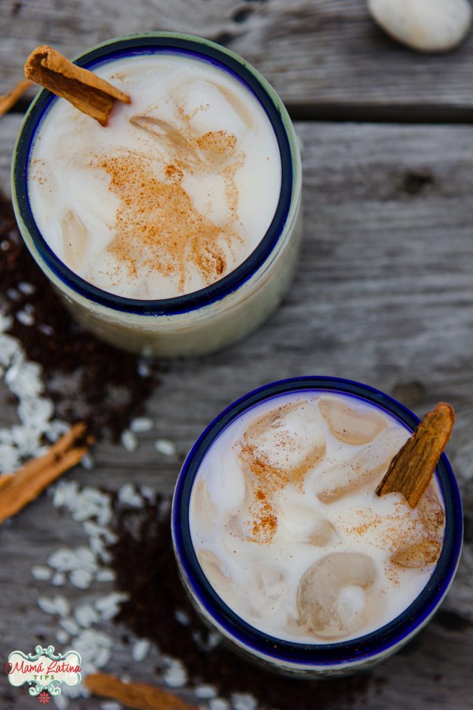 Dos vasos con agua de horchata y canela sobre una mesa de madera