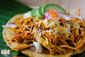 chicken pibil tostada with avocado and cheese