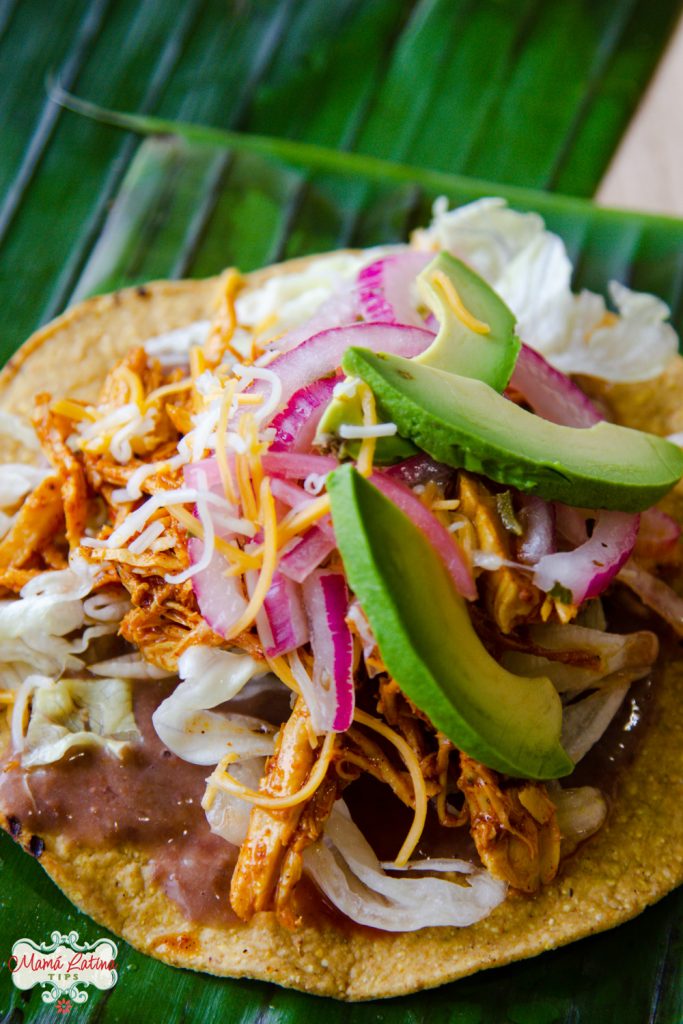 tostada con frijoles, lechuga, pollo pibil, aguacate, cebolla morada y queso vista desde arriba