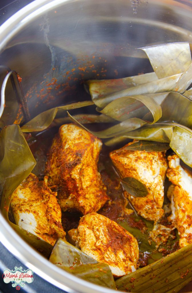 pollo pibil cocido en trozos grande dentro de una olla de presión cubierta de hojas de plátano