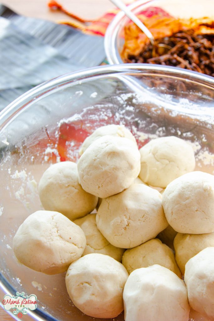 A glass bowl with balls of fresh corn masa for tamales