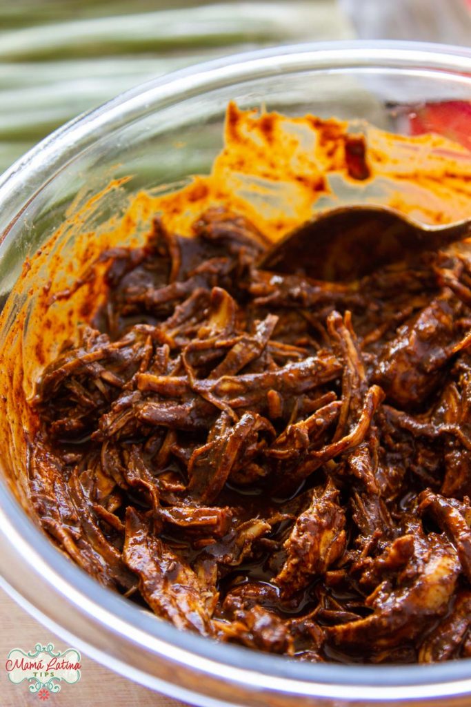 Shredded chicken with mole sauce in a glass bowl