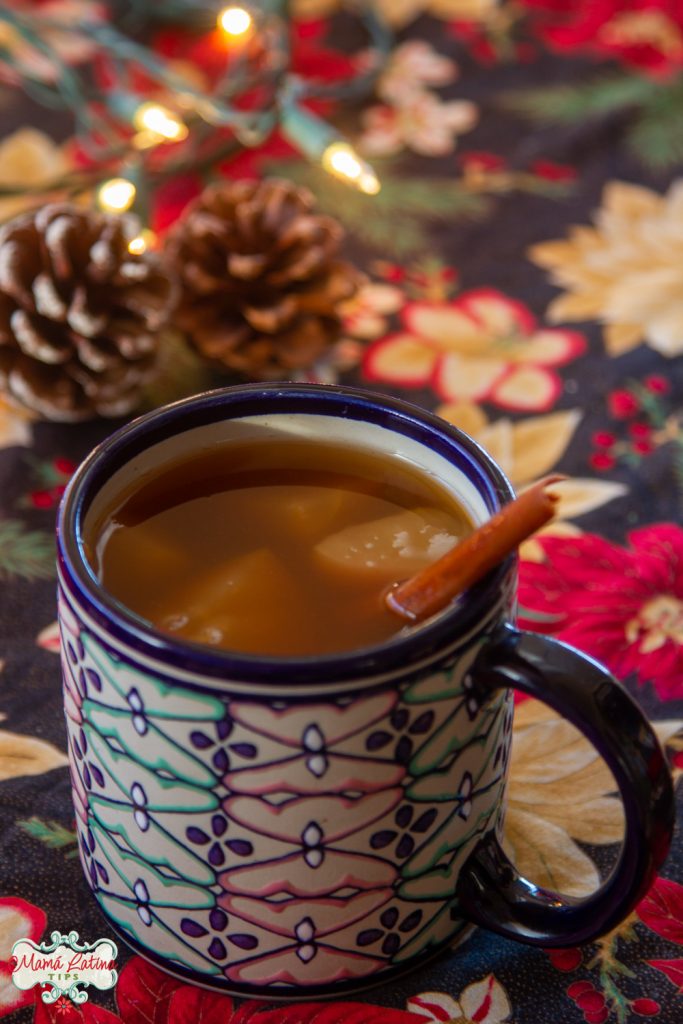 mexican ponche in a ceramic cup garnished with a cinnamon stick on a Christmas table