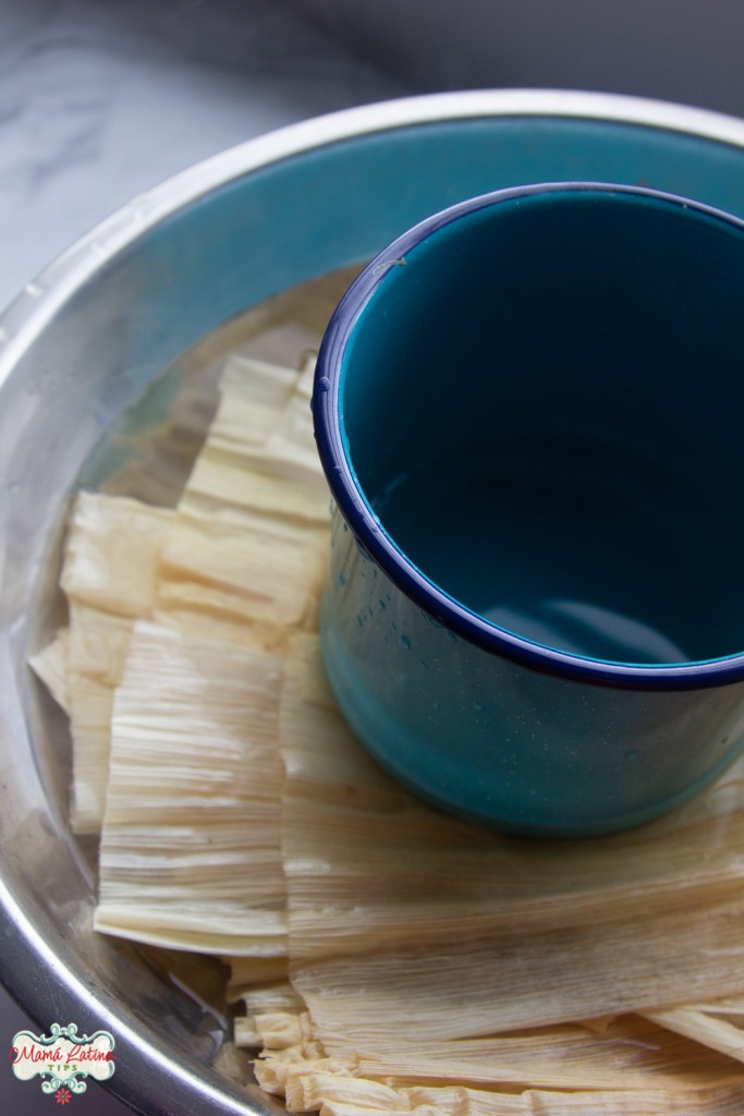 corn husks soaking in a bowl with a pot on top of them