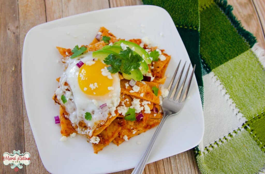 Red chilaquiles with a sunny side egg, cheese, red onion and avocado