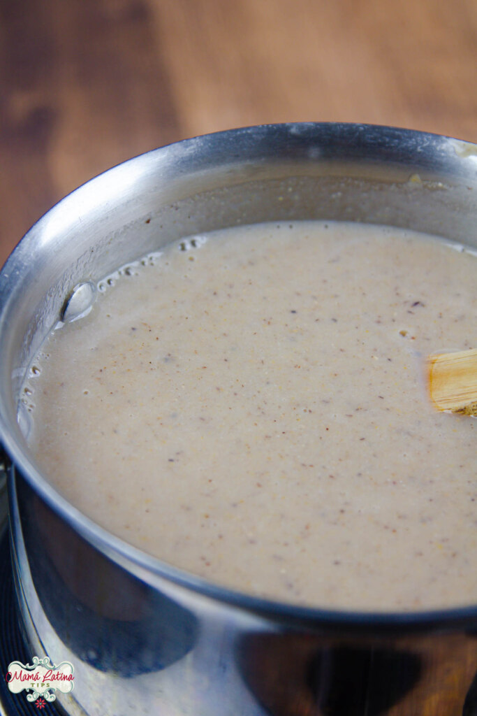 atole de frutas del ponche in a pot on top of a wooden table.