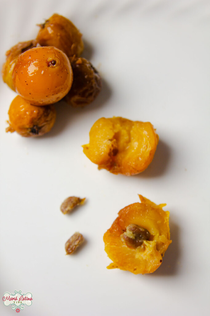 A bunch of cooked tejocotes, one of them open in half. There are two tejocotes seeds on the left side. 