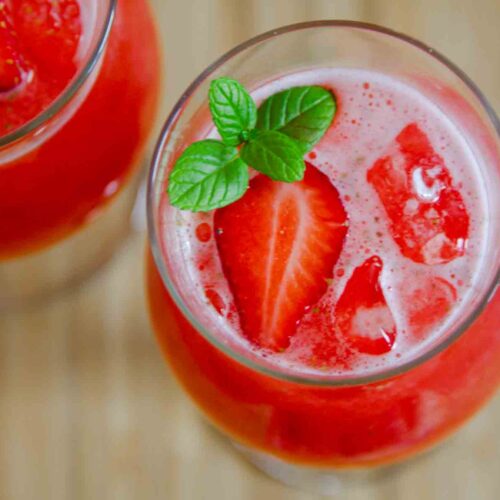 Strawberry agua fresca in a glass with ice and mint leaves