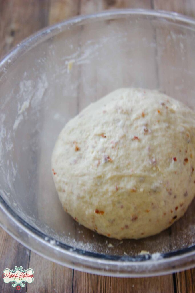 Dough in a bowl on top of a wooden table.