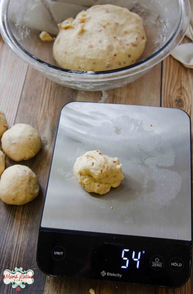 A scale with dough on it next to a bowl of dough.