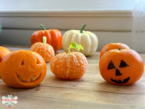 A group of Mandarin Orange pumpkins with jack o lantern faces on them.