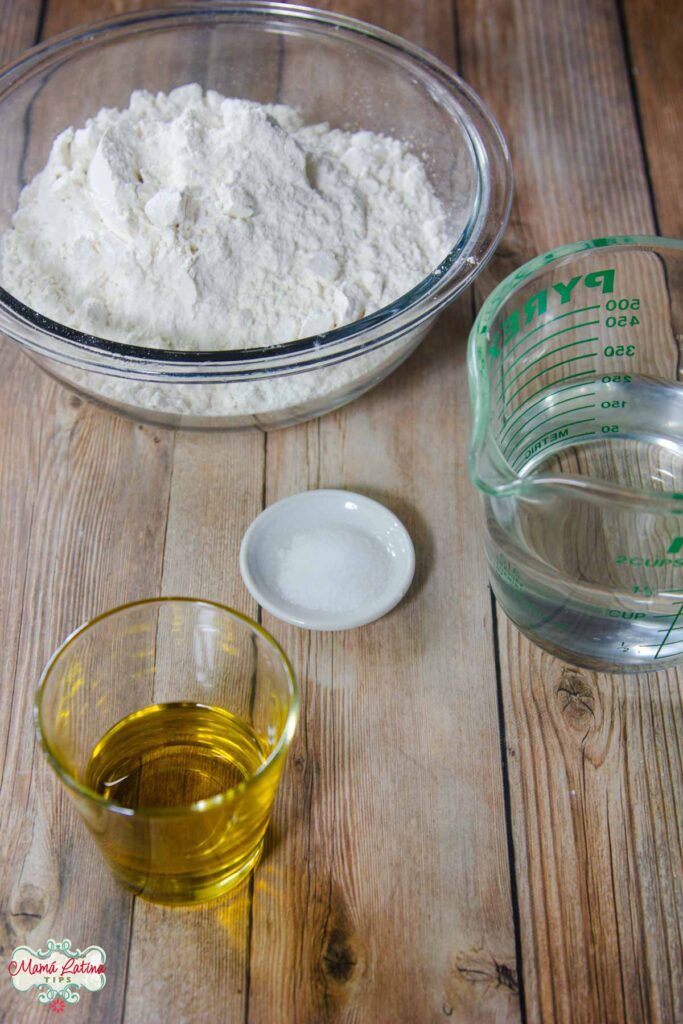 An easy homemade recipe with a bowl of flour, eggs, and oil on a wooden table.