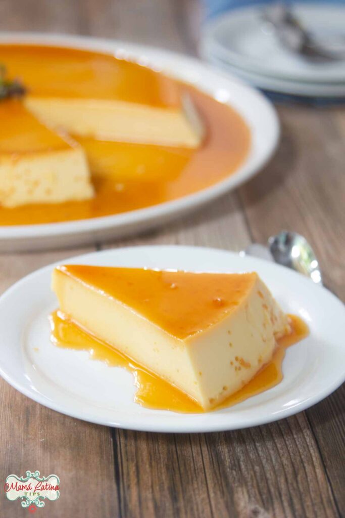 Una rebanada de Flan de Vainilla en un plato. Detrás se puede ver el flan completo en un platón.