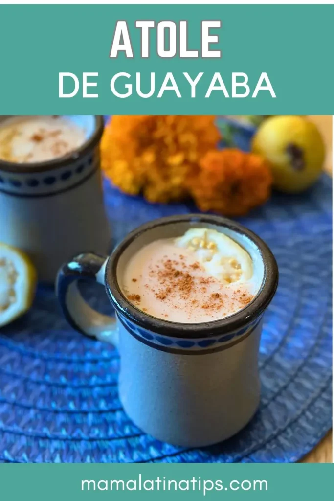 Dos tazas de Guayaba Atole, una bebida tradicional mexicana, reposan sobre un tapete azul cubierto de canela. Guayabas enteras y flores de cempasúchil decoran el fondo. El texto superior dice "Atole de Guayaba.