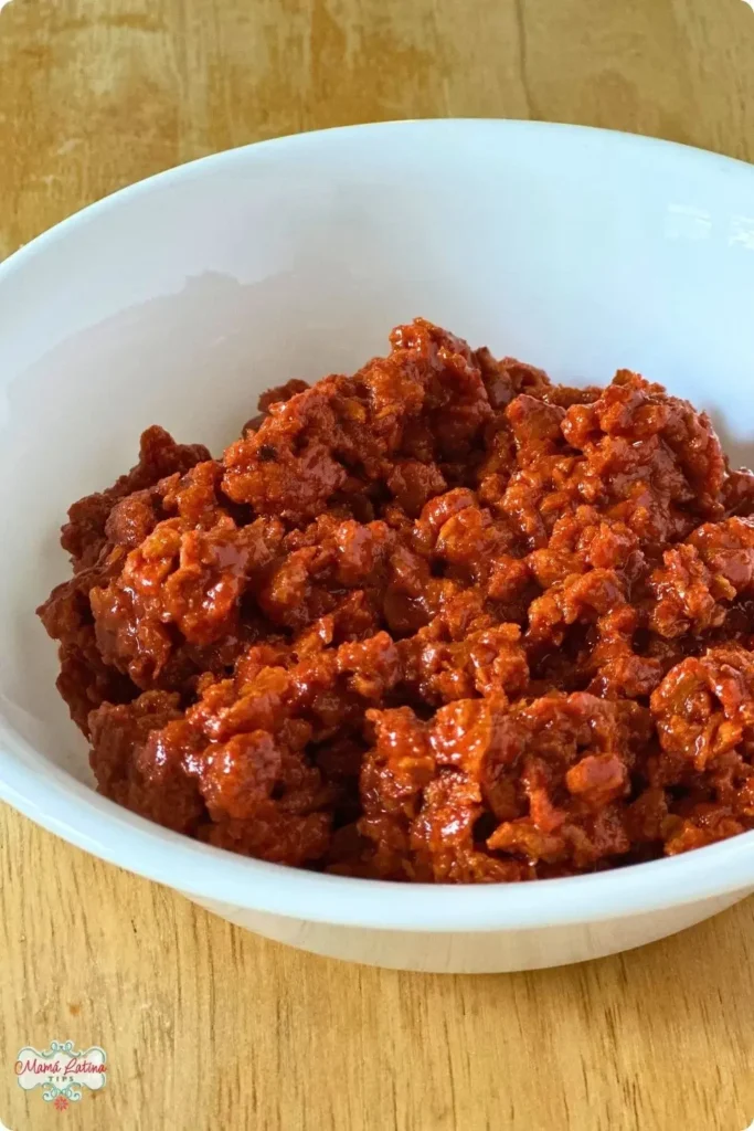 A white bowl filled with Mexican Chorizo sausage sits on a wooden surface, ready to be enjoyed in classic dishes like Papas con Chorizo.